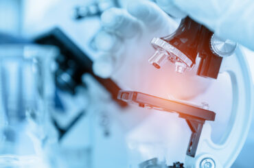 Close Up Scientist using microscope in laboratory room while making medical testing and research